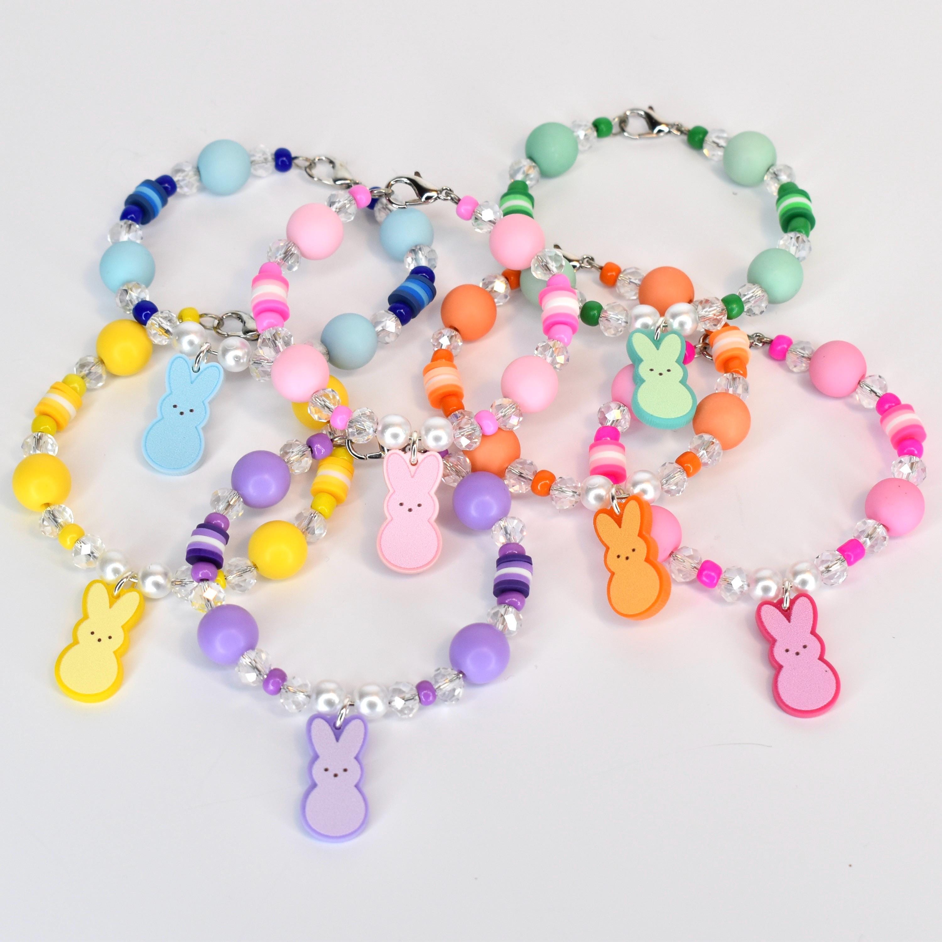 A collection of colorful beaded bracelets with various pastel-colored beads and clear crystal accents. Each bracelet features a charm shaped like a bunny in shades of yellow, blue, pink, orange, green, and purple.