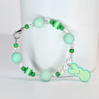 A beaded bracelet featuring mint green and clear beads, with a small bunny charm. The bracelet includes round and cylindrical beads in shades of green and white, and is secured with a silver clasp.