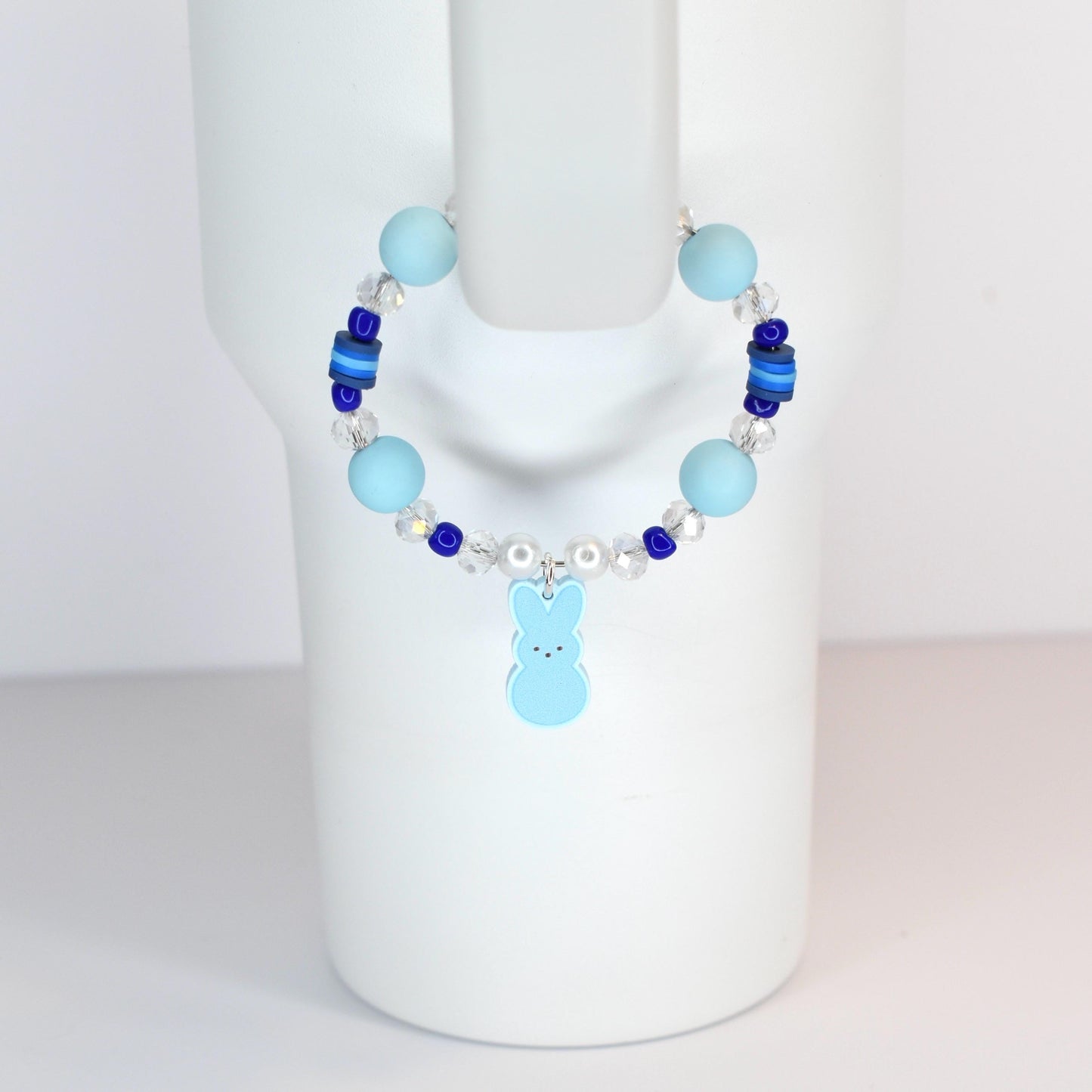 A light blue beaded bracelet with a bunny charm. The bracelet features light blue and dark blue beads, clear crystal beads, and a light blue bunny charm. The bracelet is displayed on a white mannequin.
