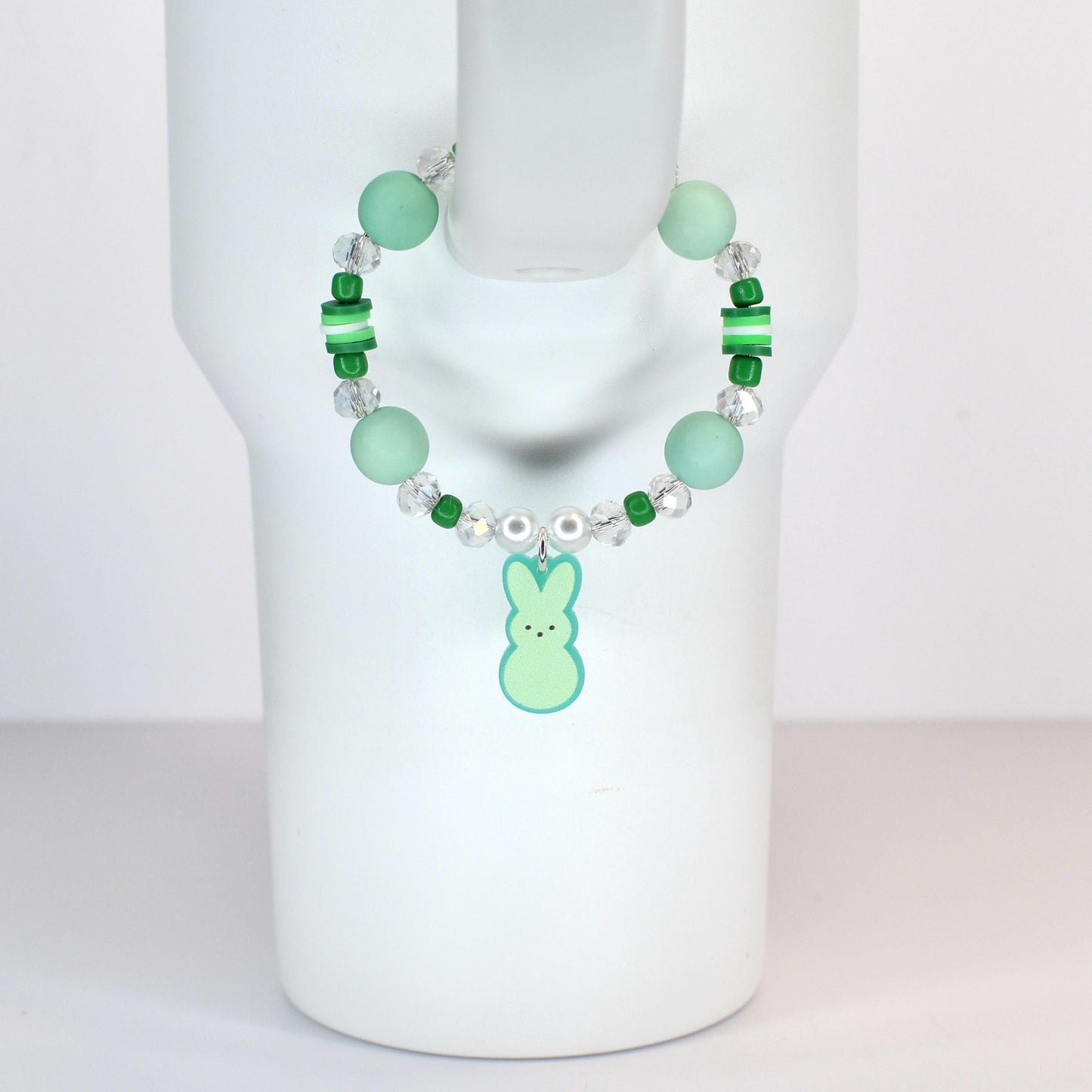 A beaded handle bracelet featuring mint green and clear beads, with a light green bunny charm. The bracelet includes larger round beads, smaller green beads, and clear crystal-like beads. The bunny charm has a light green body and a darker green outline.