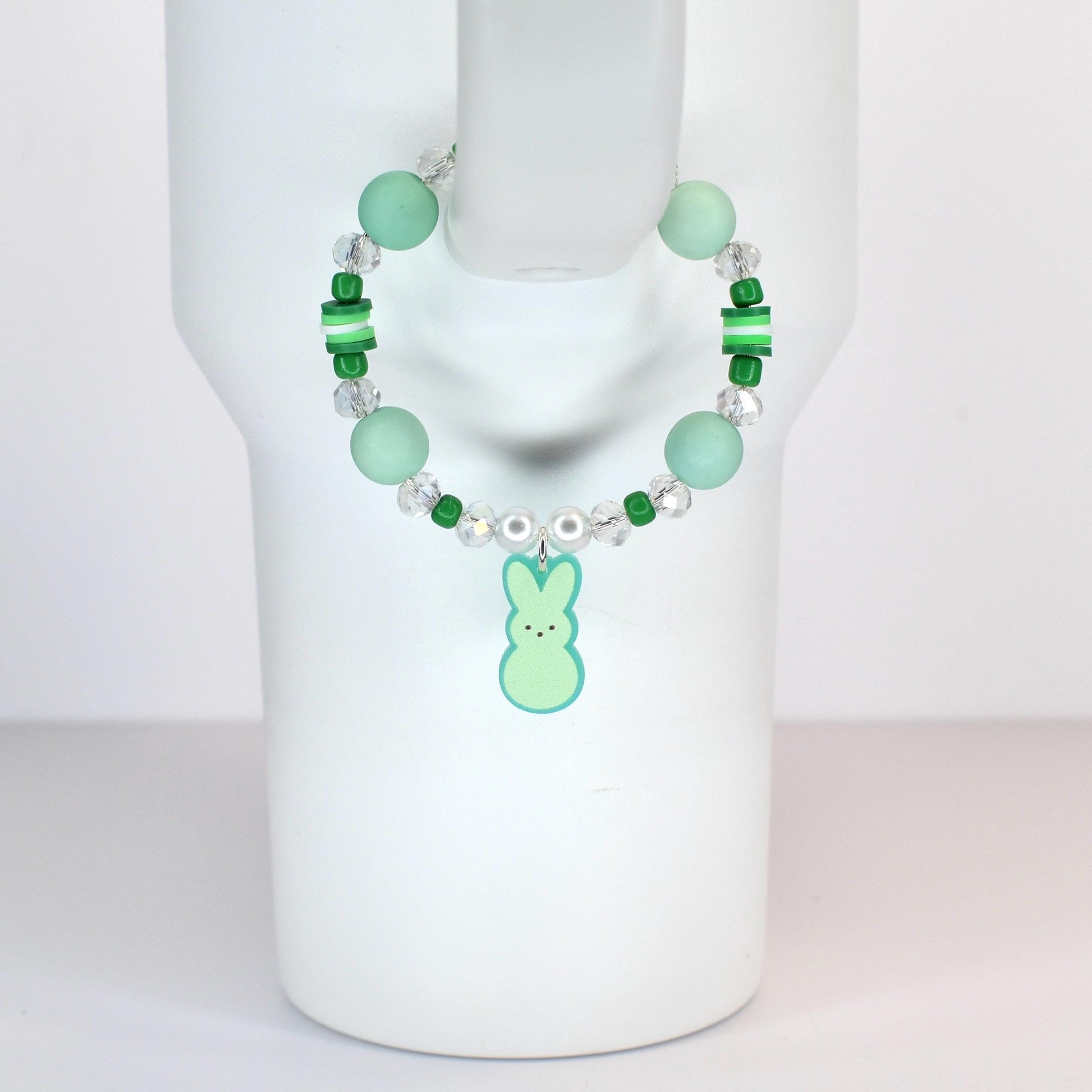 A beaded handle bracelet featuring mint green and clear beads, with a light green bunny charm. The bracelet includes larger round beads, smaller green beads, and clear crystal-like beads. The bunny charm has a light green body and a darker green outline.