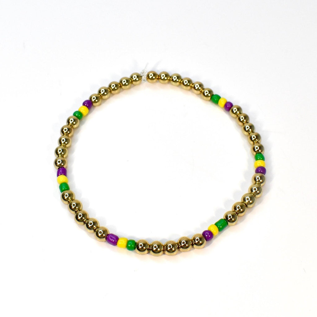 Gold beaded bracelet with alternating sections of purple, yellow, and green beads. The bracelet is made of small, round gold beads, with the colorful beads interspersed throughout. The bracelet is displayed on a white background.