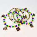 A collection of Mardi Gras beaded necklaces in green, gold, and purple. Each necklace features a variety of beads and decorative charms, including a fleur-de-lis, a mask, and a beer stein.