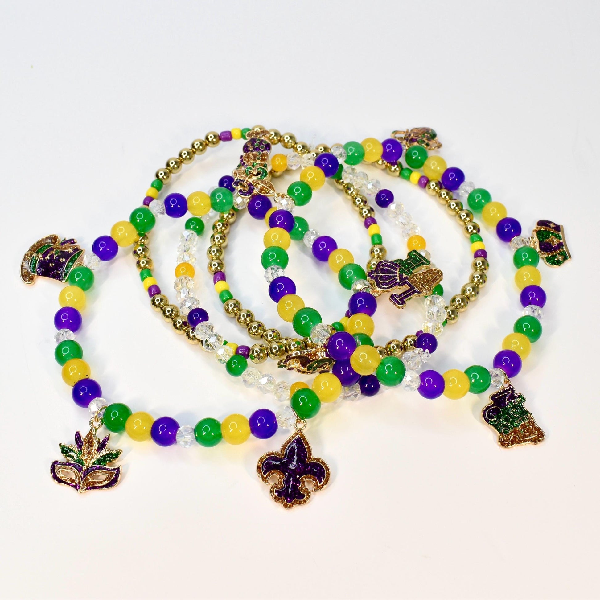 A collection of Mardi Gras beaded necklaces in green, gold, and purple. Each necklace features a variety of beads and decorative charms, including a fleur-de-lis, a mask, and a beer stein.