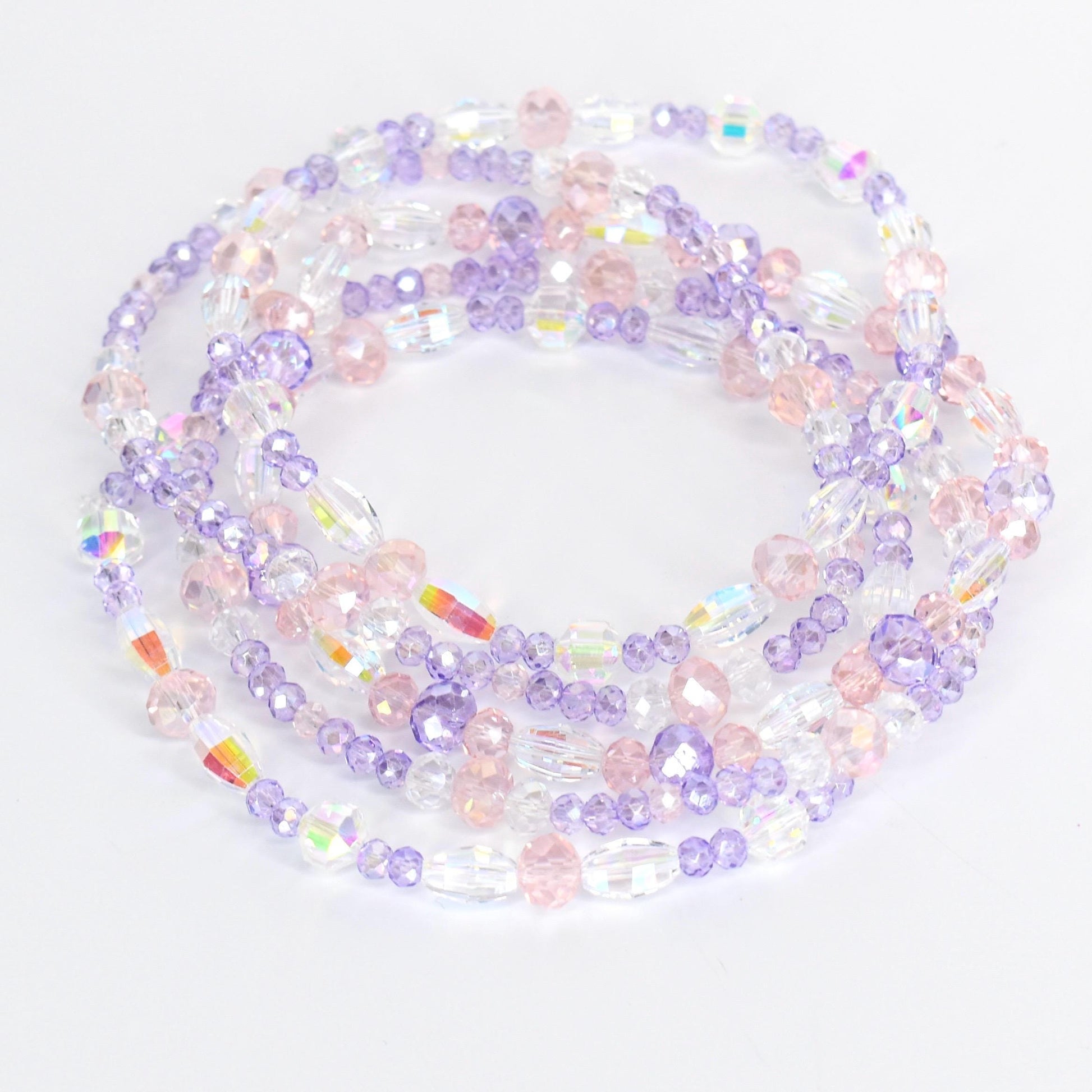 Strands of beaded jewelry in shades of clear, pink, and lavender. The beads are various shapes and sizes, including round and oval. The jewelry is arranged in a circular pattern, with the beads reflecting light.