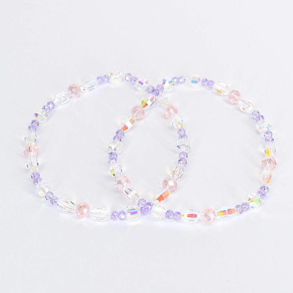 Two beaded bracelets. Each bracelet features a mix of clear, iridescent, pink, and purple beads. The beads are strung together to form a circular shape. The bracelets are displayed on a white background.