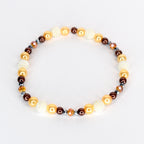 A beaded bracelet featuring a mix of colors and textures. The bracelet includes gold, brown, and white beads, along with faceted crystal accents. The beads are strung together to form a circular shape.