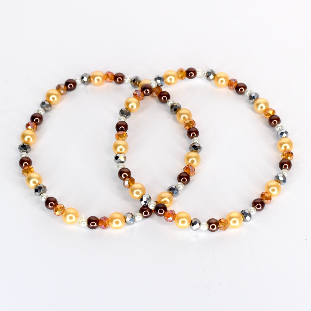 Two beaded bracelets. One bracelet features golden, brown, and silver beads. The other bracelet has a similar design, with golden, brown, and silver beads. The bracelets are on a white background.