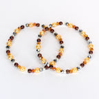 Two beaded bracelets. One bracelet features golden, brown, and silver beads. The other bracelet has a similar design, with golden, brown, and silver beads. The bracelets are on a white background.