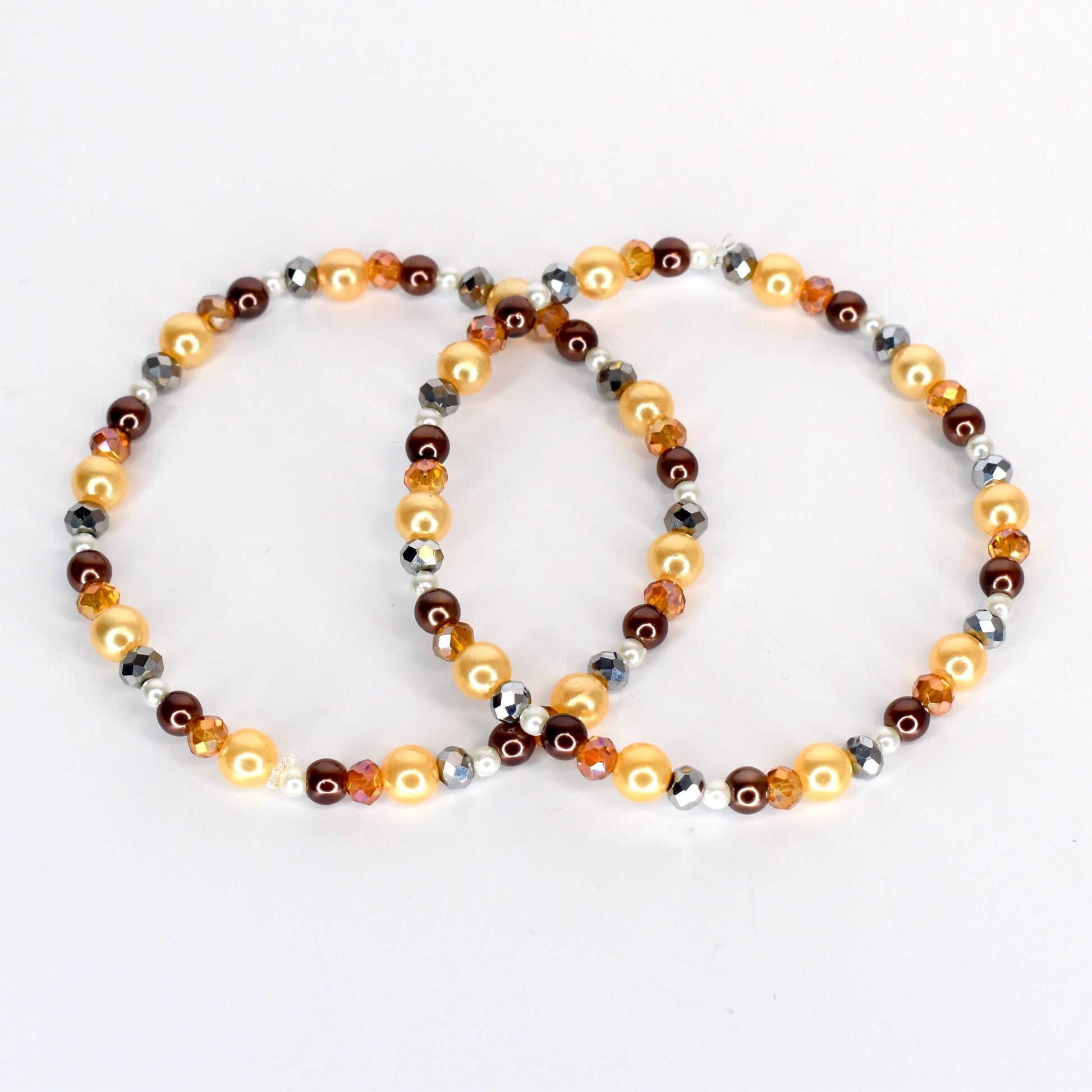 Two beaded bracelets. One bracelet features golden, brown, and silver beads. The other bracelet has a similar design, with golden, brown, and silver beads. The bracelets are on a white background.