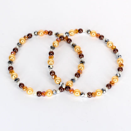 Two beaded bracelets. One bracelet features golden, brown, and silver beads. The other bracelet has a similar design, with golden, brown, and silver beads. The bracelets are on a white background.