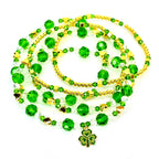 A collection of beaded st Patricks day bracelets in shades of green, gold, and clear. The bracelets feature round green beads, gold-colored accents, and a shamrock charm. The bracelets are arranged in a layered style, creating a festive look.