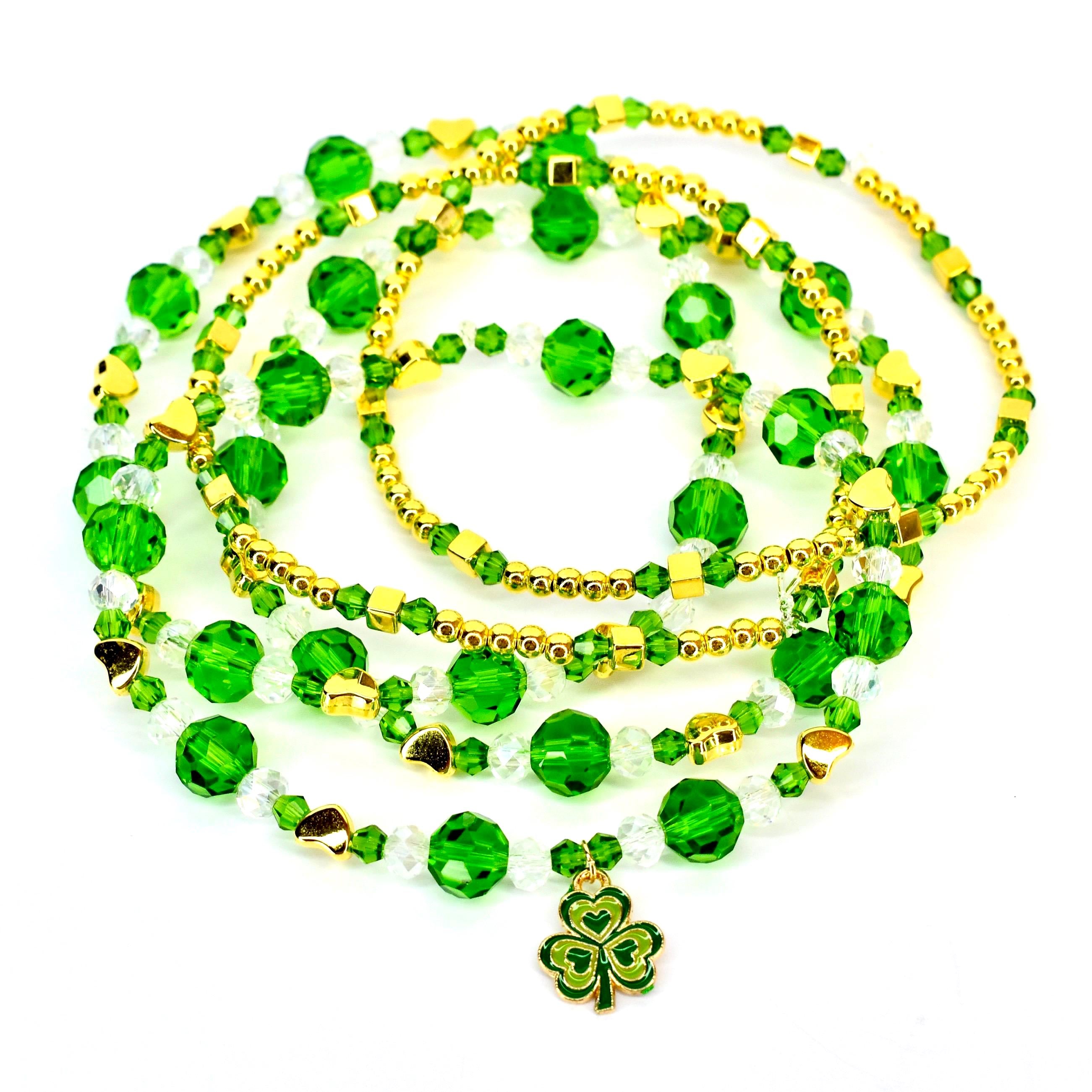 A collection of beaded st Patricks day bracelets in shades of green, gold, and clear. The bracelets feature round green beads, gold-colored accents, and a shamrock charm. The bracelets are arranged in a layered style, creating a festive look.