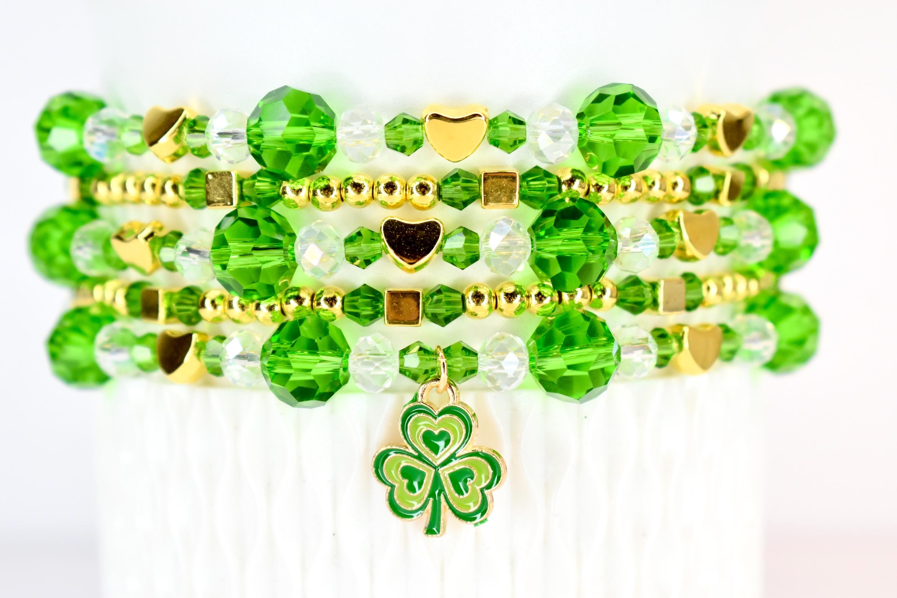 Stack of beaded st Patricks day bracelets featuring green and clear crystal beads, gold heart and square accents, and a shamrock charm. The bracelets are stacked on top of each other, creating a layered look. The bracelets are approximately 0.5 inches wide.