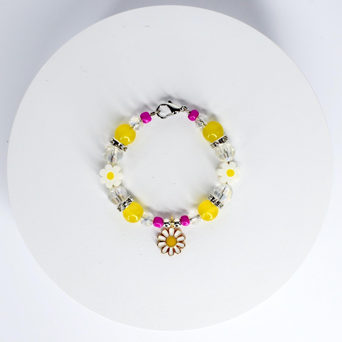 A beaded tumbler handle bracelet featuring yellow, clear, and pink beads. The bracelet includes white daisy-shaped beads and a daisy charm. The beads are strung on a silver-colored chain with a clasp.