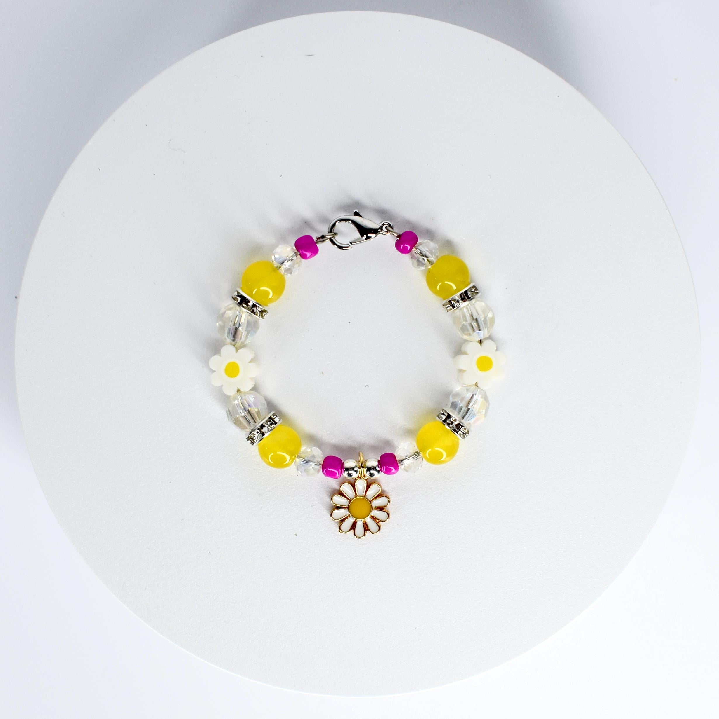 A beaded tumbler handle bracelet featuring yellow, clear, and pink beads. The bracelet includes white daisy-shaped beads and a daisy charm. The beads are strung on a silver-colored chain with a clasp.