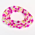 A collection of beaded bracelets in shades of pink, yellow, and clear. The beads are strung together with silver-colored accents. The waist beads are arranged in a circular pattern against a white background.
