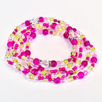 A collection of beaded bracelets in shades of pink, yellow, and clear. The beads are strung together with silver-colored accents. The waist beads are arranged in a circular pattern against a white background.