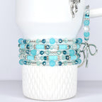 Stack of beaded bracelets in shades of blue and clear. The bracelets feature various bead sizes and shapes, including round, faceted, and disc-shaped beads. The bracelets are displayed on a white tumbler.