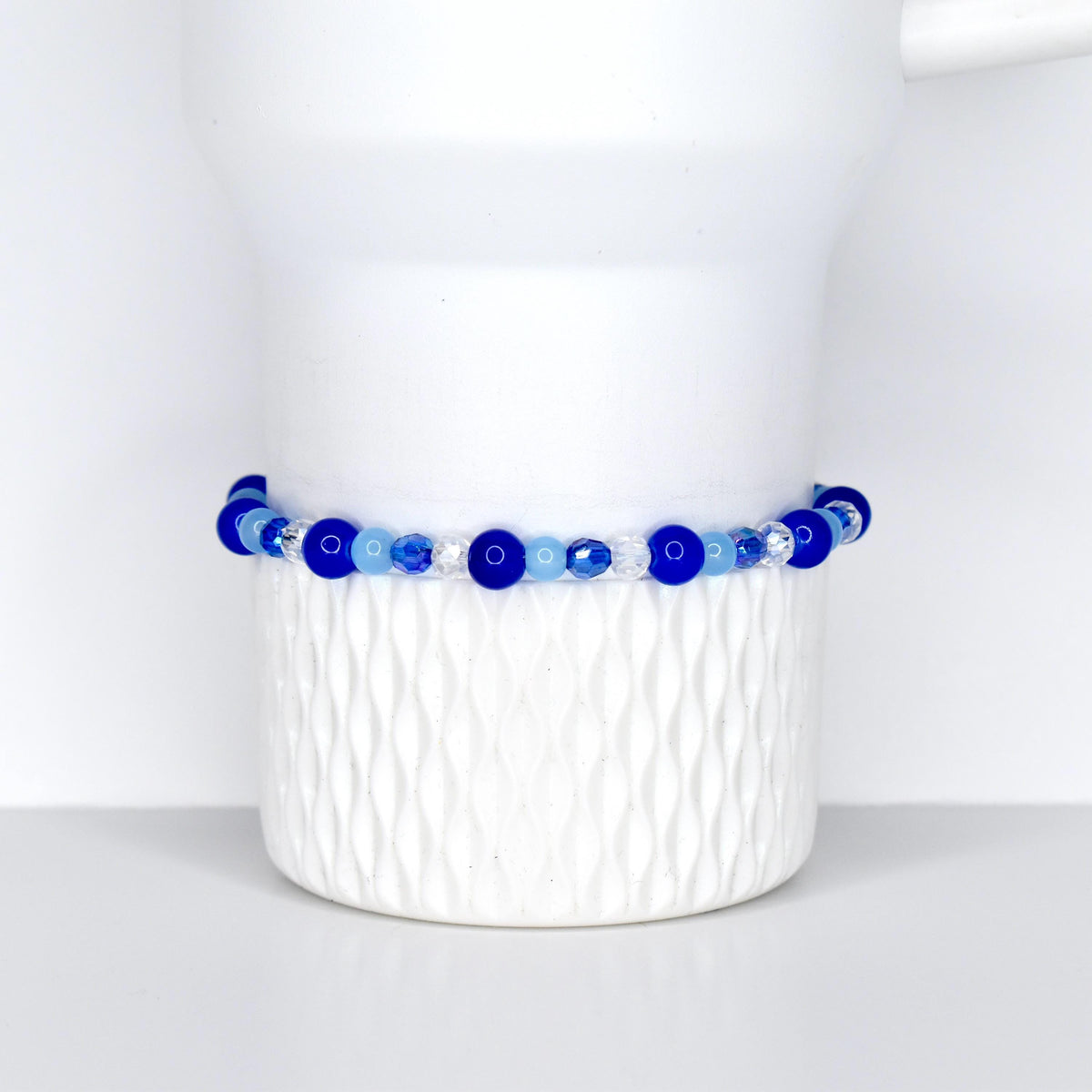A cobalt blue, sky blue and crystal beaded tumbler bracelet on a white Stanley tumbler. Made for cobalt blue stanley and sky blue stanley.