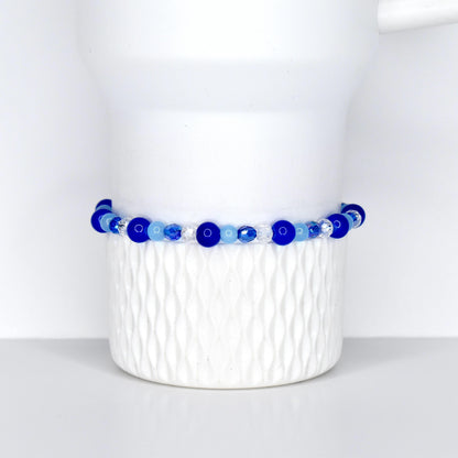 A cobalt blue, sky blue and crystal beaded tumbler bracelet on a white Stanley tumbler. Made for cobalt blue stanley and sky blue stanley.