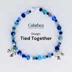 A beaded bracelet with a variety of blue beads, including faceted and round shapes, and silver-colored bow charms. The text "Calathea Collective" and "Design: Tied Together" are also visible.