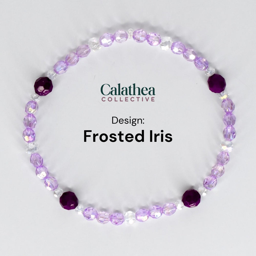 A bracelet featuring a design called "Frosted Iris." The bracelet is composed of small, light purple and clear beads, with larger, deep purple beads interspersed throughout. The text "Calathea Collective" and "Design: Frosted Iris" are also visible.