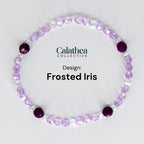 A bracelet featuring a design called "Frosted Iris." The bracelet is composed of small, light purple and clear beads, with larger, deep purple beads interspersed throughout. The text "Calathea Collective" and "Design: Frosted Iris" are also visible.