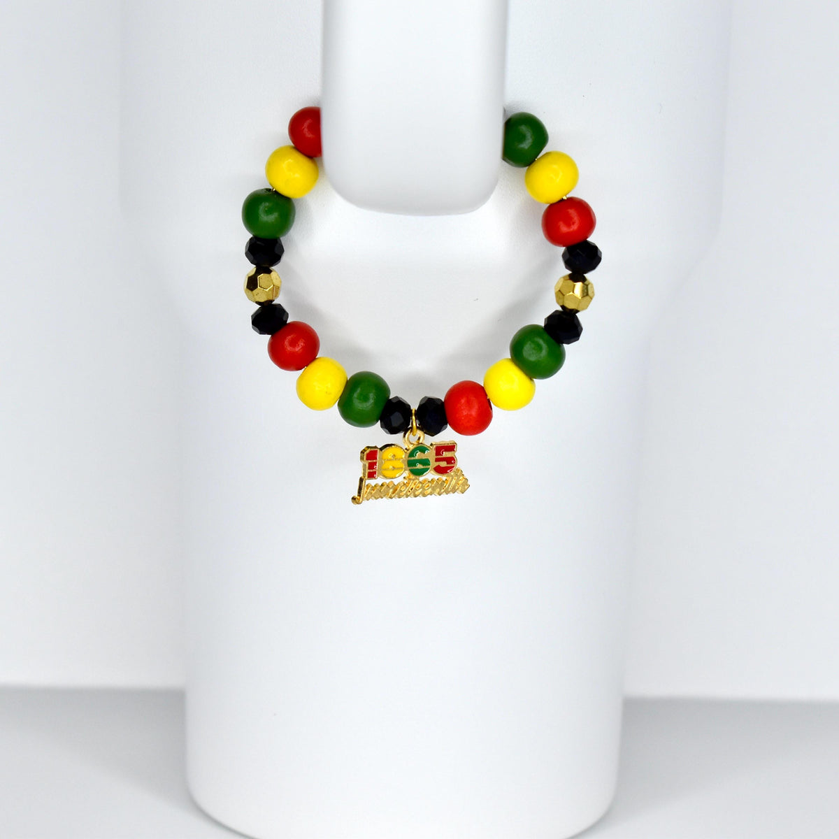 A beaded tumbler handle charm with red, yellow, green, black, and gold beads. A gold charm with the text "1865 Juneteenth" hangs from the bracelet. The bracelet is displayed on a white form.