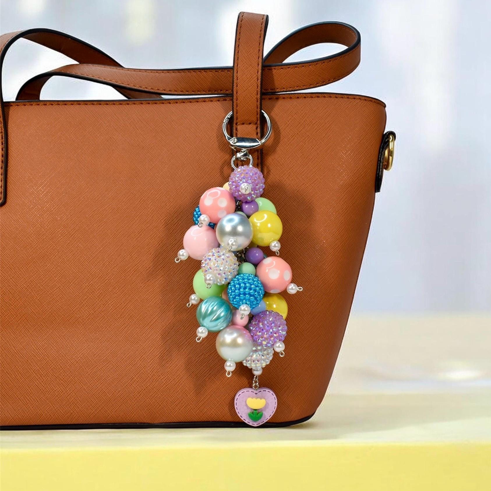 Pastel spring bag charm with colorful beaded cluster featuring glossy and textured beads in pink, yellow, blue, purple, and green, finished with pearl accents and a heart flower charm. Whimsical handmade purse accessory and statement keychain.