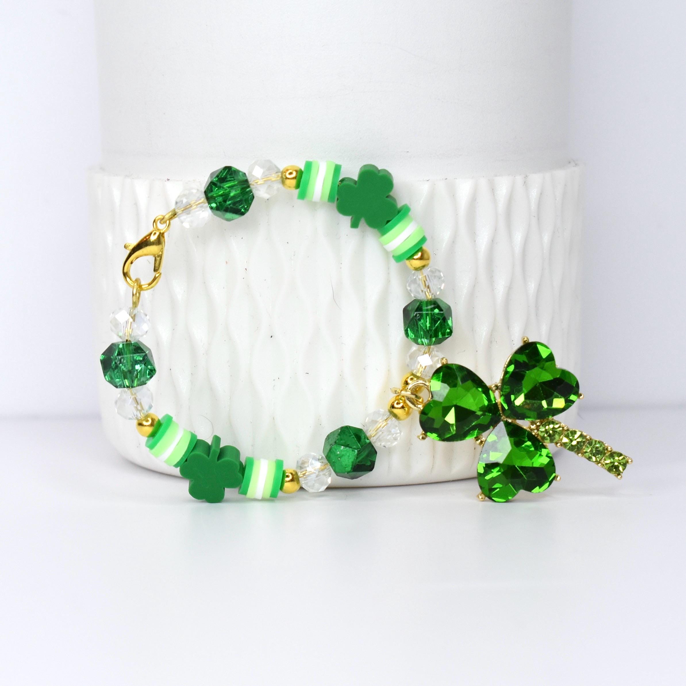 A St. Patrick's Day tumbler handle bracelet featuring green shamrock charms and beads. The bracelet includes green, white, and gold accents, with a large shamrock pendant.