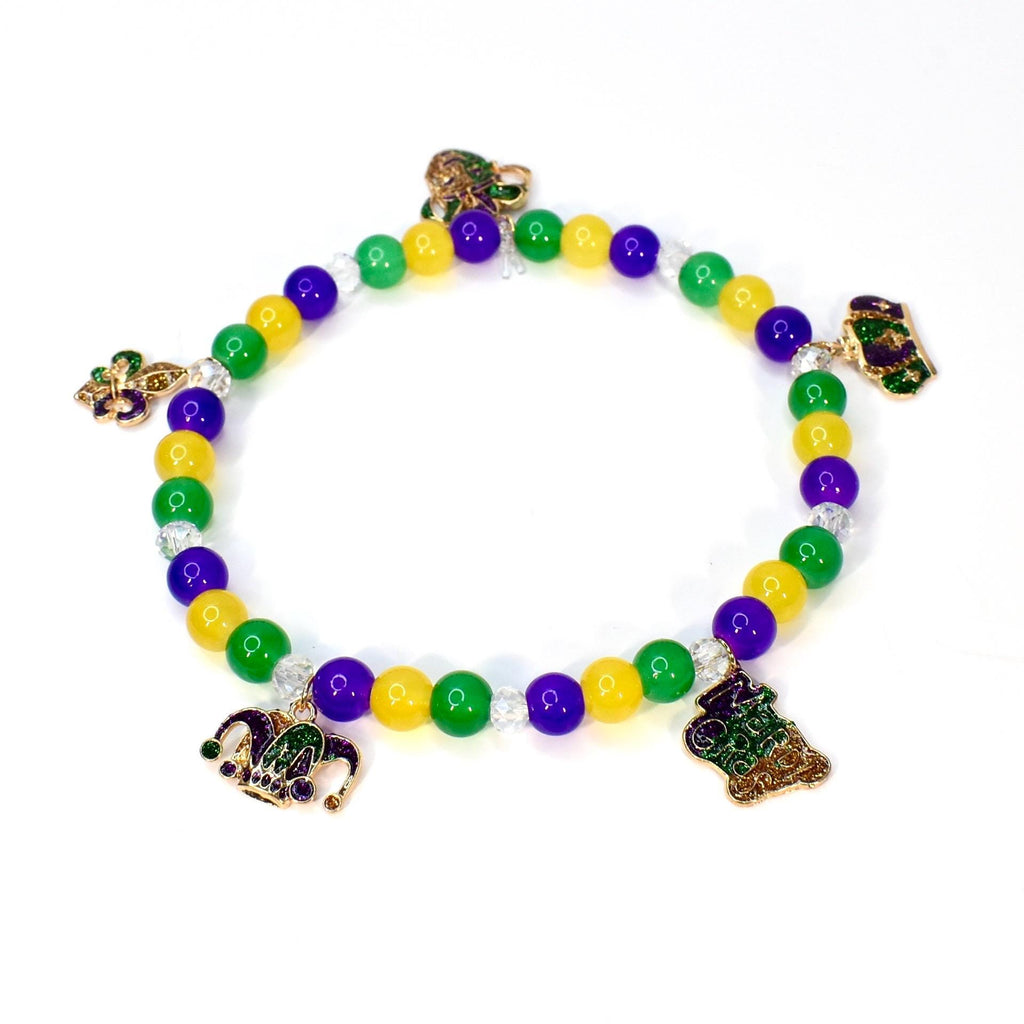 A beaded bracelet featuring green, yellow, and purple beads, with decorative charms. The charms include a fleur-de-lis, a jester's hat, and a decorative emblem. The bracelet is designed with a stretchable band, suitable for various wrist sizes.