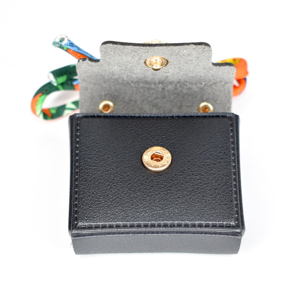 A small, black, rectangular wallet with a gold snap closure. The interior is gray, and the wallet is open, revealing a colorful strap. The wallet is made of a textured material.