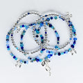 Several beaded bracelets in shades of blue and silver. The bracelets feature a mix of small, round silver beads and larger, faceted blue beads. Some bracelets have silver charms in the shape of flowers and a ribbon.
