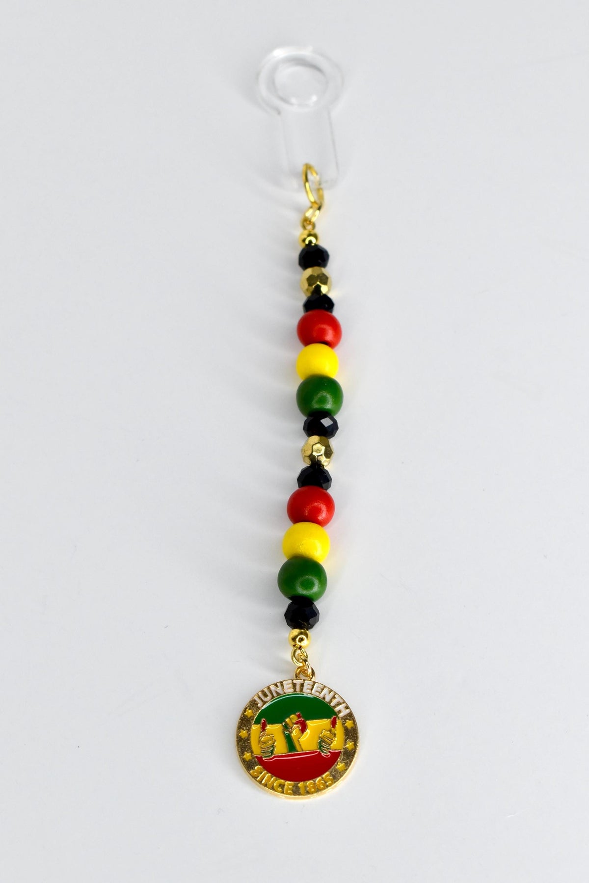 A Juneteenth-themed straw charm with a clear plastic straw adapter at the top. The charm features a string of red, yellow, green, and black beads, and a gold-colored pendant with the words "Juneteenth Since 1865" and a graphic of two hands.