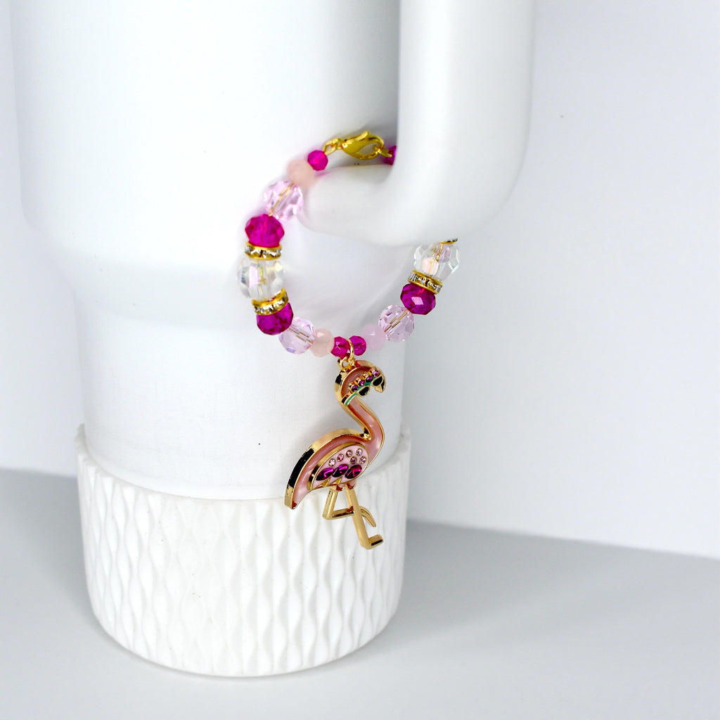 A beaded bracelet with a flamingo charm. The bracelet features pink, clear, and gold beads. The flamingo charm is pink with jewel accents and gold-colored legs.