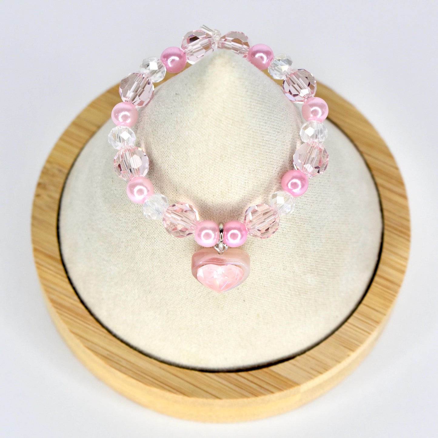 A pink beaded 17cm monster doll necklace with a heart charm. The necklace features a mix of pink and clear beads, including round pearls and faceted crystals. The heart charm is a light pink color.
