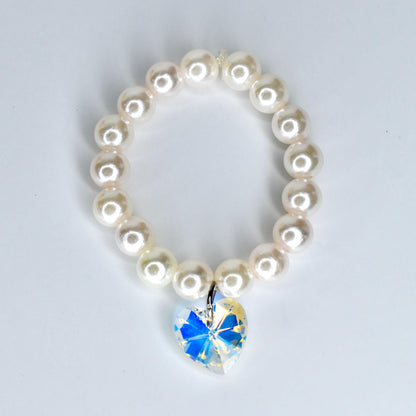 A pearl 17cm monster doll necklace with a heart-shaped pendant. The necklace features round, off-white pearls strung together. The pendant is a clear crystal with a blue and yellow iridescent effect, shaped like a heart.
