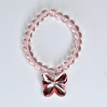A pink beaded 17cm monster doll necklace with a butterfly pendant. The necklace features translucent pink beads strung together. The butterfly pendant is a darker shade of pink and has a reflective, faceted design. The necklace is designed to be worn around the wrist.