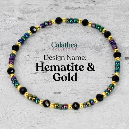 A beaded bracelet with the text "Calathea Collective" and "Design Name: Hematite & Gold". The bracelet features black, gold, and iridescent beads. The beads are strung together to form a circular shape.