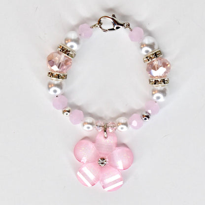A pink and white beaded tumbler handle bracelet with a flower charm. The tumbler charm features pink and white beads, clear crystal accents, and a silver clasp. The flower charm is pink with white stripes and a crystal center.