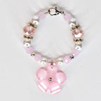 A pink and white beaded tumbler handle bracelet with a flower charm. The tumbler charm features pink and white beads, clear crystal accents, and a silver clasp. The flower charm is pink with white stripes and a crystal center.