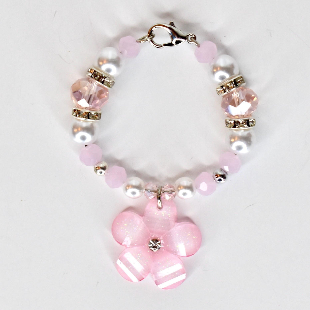 A pink and white beaded tumbler handle bracelet with a flower charm. The tumbler charm features pink and white beads, clear crystal accents, and a silver clasp. The flower charm is pink with white stripes and a crystal center.