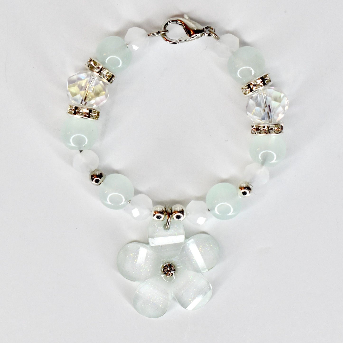 A delicate tumbler handle bracelet featuring a flower charm and a mix of light blue and white beads. The tumbler bracelet has a silver clasp and decorative crystal beads. The flower charm has a central crystal accent.