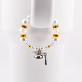 A graduation-themed tumbler handle bracelet featuring large white faux pearls, clear crystal beads, and gold accents. A silver graduation cap charm with a black tassel hangs from the bracelet. The bracelet is displayed against a white background.