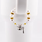 A graduation-themed tumbler handle bracelet featuring large white faux pearls, clear crystal beads, and gold accents. A silver graduation cap charm with a black tassel hangs from the bracelet. The bracelet is displayed against a white background.
