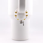 A white beaded cup charm with a graduation cap charm. The charm features white faux pearls, clear and gold-colored beads. The graduation cap charm is silver with a black tassel.