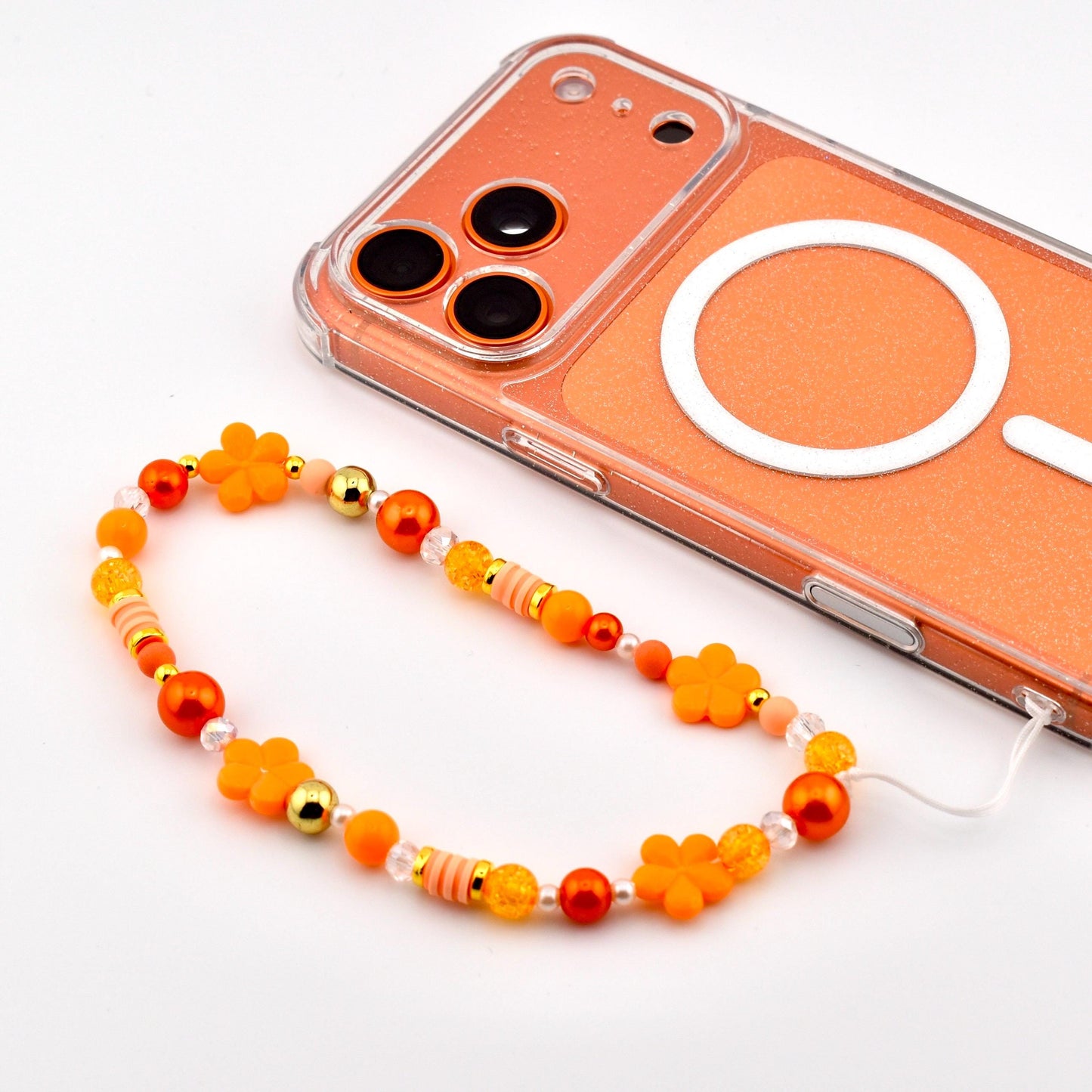 An orange phone with a clear border and a beaded phone charm. The charm features orange flower beads, gold beads, and various orange and clear beads.