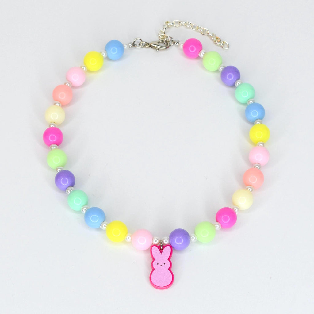 A colorful beaded necklace featuring a variety of pastel-colored beads, including pink, yellow, blue, green, and purple. A pink bunny charm hangs from the center. The necklace is secured with a silver-colored clasp.