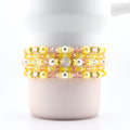 A set of five handmade beaded bracelets in yellow, pink and pearl.